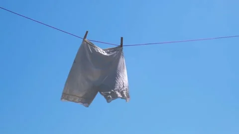 Vintage white knickers are drying rope against sky, swaying in wind. slow motion Stock Footage 230117670