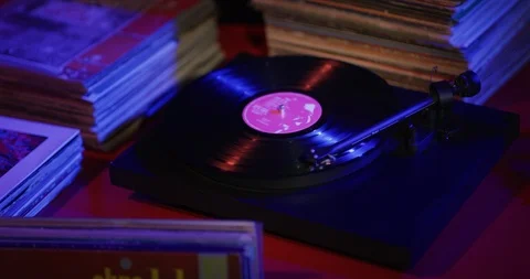 Vinyl record playing on turntable with amongst a stack of records. Stock Footage 112598575