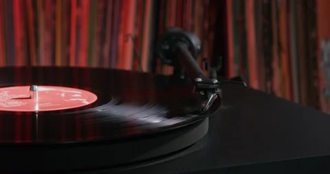 Vinyl record playing on turntable with a bunch of records in the background. Stock Footage 112598542