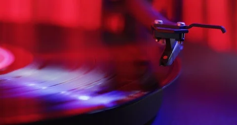 Vinyl record playing on turntable with a stack of records in the background. Stock Footage 112598461