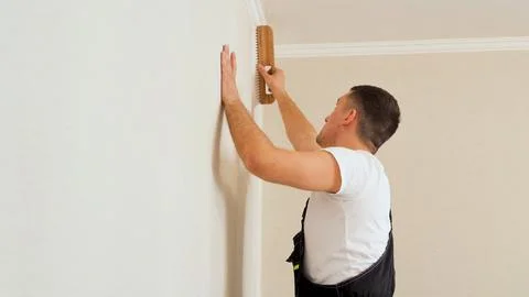 Vinyl wallpapers squeegee tool in use by professional interior renovation worker Stock Photos