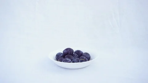 Violet Blue Plum Falling on a Plate. Blue Plum Drops on White Background. Slow M Stock Footage 94944134