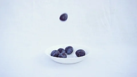 Violet Blue Plum Falling on a Plate. Blue Plum Drops on White Background. Slow M Stock Footage 94944230