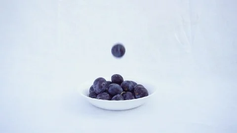 Violet Blue Plum Falling on a Plate. Blue Plum Drops on White Background. Slow M Stock Footage 94944275