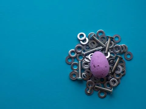 Violet Easter egg on blue background with metal screws Stock Photos