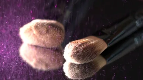 Violet glitter falling on the makeup brushes on the mirror on the black Stock Footage 75971489