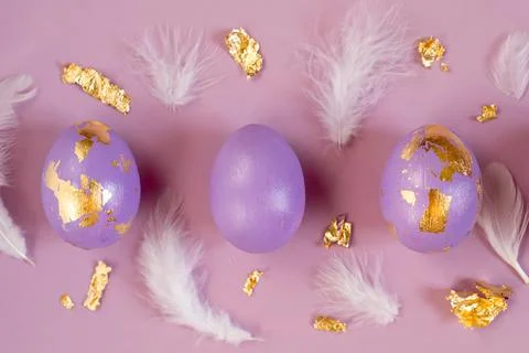 Violet, very peri Easter eggs with golden foil, feathers on violet background. Stock Photos
