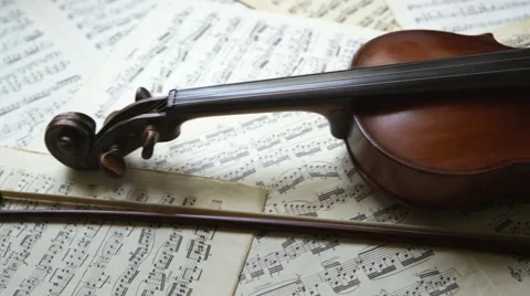 Violin with bow lying on musical notes. Violin body and fiddlestick dolly shot Stock Footage 65419096