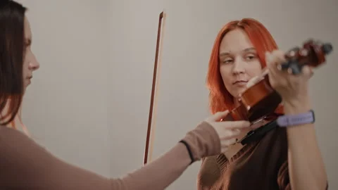 Violin lesson scene. Tutor corrects posture during intimate violin instruction Stock Footage 346555464