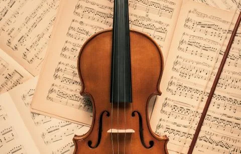 Violin lying on the old music notes Stock Photos