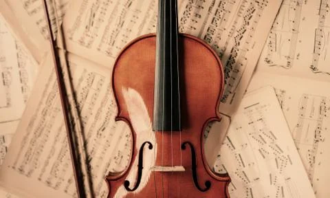 Violin lying on the old music notes Stock Photos
