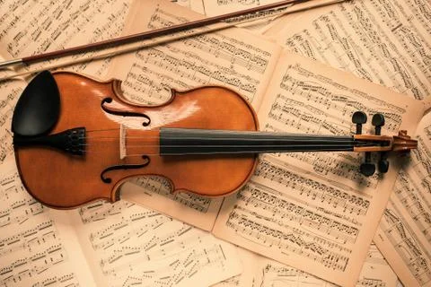 Violin lying on the old music notes Stock Photos