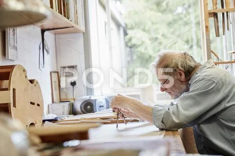 A violin maker at his drawing board drawing out the plans Stock Photos