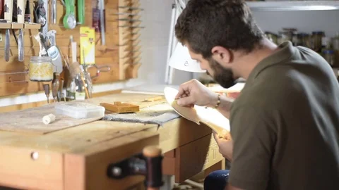 Violin maker scratching violin on desk Stock Footage 75947310