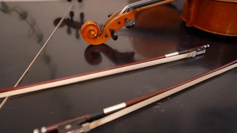 Violin scroll and two bows on glossy black table Video stock 347813828