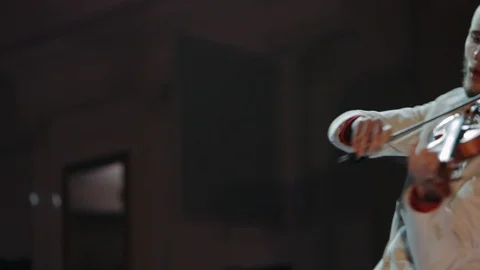 Violinist with hair bundle performs on stage against blurred colorful lights Stock Footage 119019367