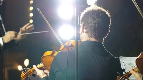 Violinist playing with conductor in the back ground   Stock Footage 95779687