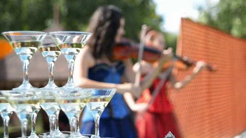 Violinists playing on the background wine glasses with champagne 库存影片 71370819