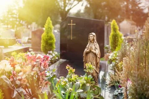 Virgin Mary at cemetery, graveyard background, in sunlight as a symbol of Stock Photos