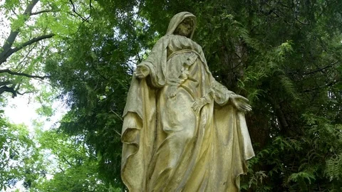 Virgin Mary Statue with open arms. On background sky and green trees. Stock Footage