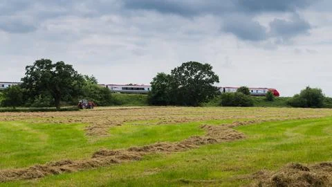 A Virgin train passes a tractor on a field Stock Photos
