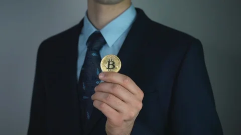 Virtual currency bitcoin concept: sharp man in a suit showing bitcoin. Crypto Stock Footage 125194165