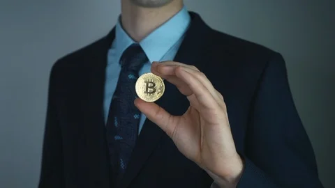 Virtual currency bitcoin concept: sharp man in a suit showing bitcoin. Crypto Stock Footage 125194261