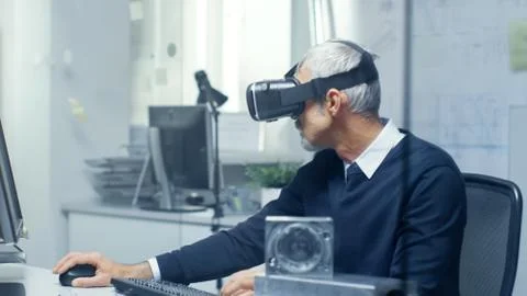 Virtual Reality Engineer Works with VR Glasses On while Simultaneously Doing  Stock Photos