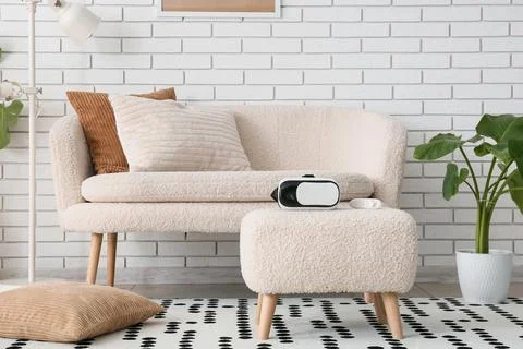 Virtual reality headset and controller on a modern living room ottoman with a Stock Photos