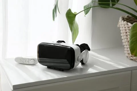 Virtual reality headset and controller on white table with green plant, immer Stock Photos