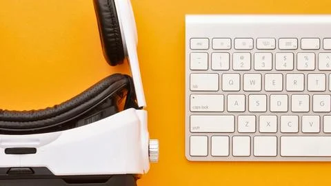 Virtual reality headset and keyboard on a vibrant orange background Stock Photos