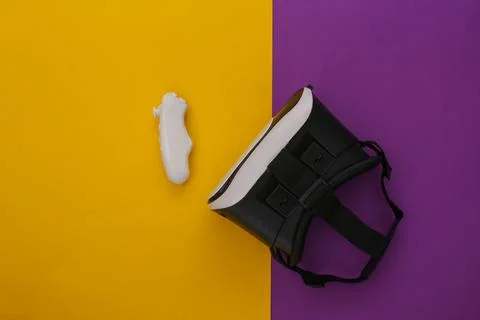 Virtual reality headset with controller on yellow-purple background. Top view Stockfoto's