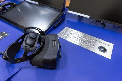 Virtual reality headset rests beside computer monitors Stock Photos