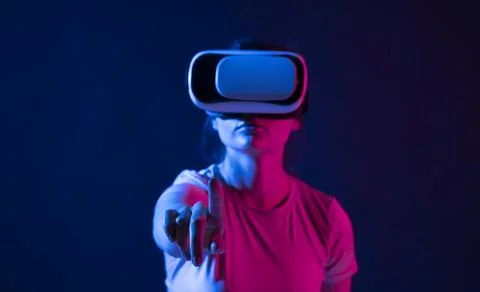 Virtual reality technology concept. Portrait of young woman stands in studio Stock Photos