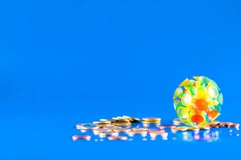 Virus knocking down a stack of different coins and money on a blue background Stock Photos