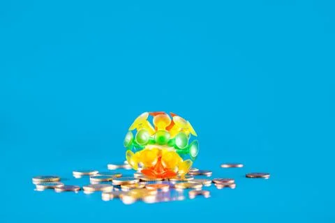 Virus knocking down a stack of different coins and money on a blue background Foto stock