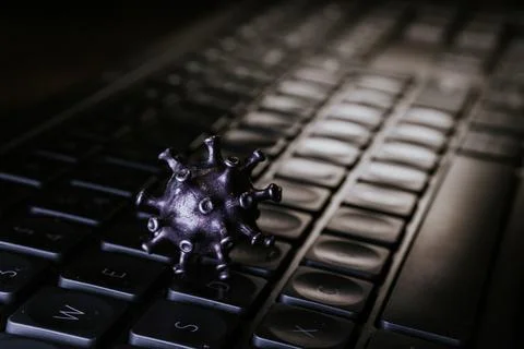 Virus model placed on a black keyboard, symbolizing the impact of technolog.. Stock Photos