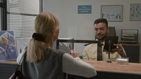 Visa Processing Officer Taking Passport from Woman, Asking Her to Remove Glasses Stock Footage 311026534