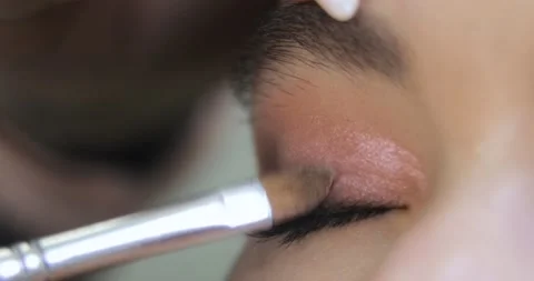 Visagist is applying eye shadows to upper eyelid of young model, eye closeup. Stock Footage 145502650