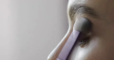 Visagist is applying eye shadows to upper eyelid of young model, eye closeup. Stock Footage 145503158