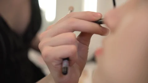 Visagiste with brush applies tone coverage on young woman's face in beauty salon Vídeos de archivo 129524366
