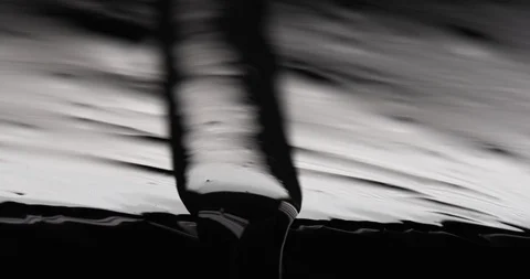 Viscous fluid flowing down a sharp edge in black and white look Stock Footage 104427954