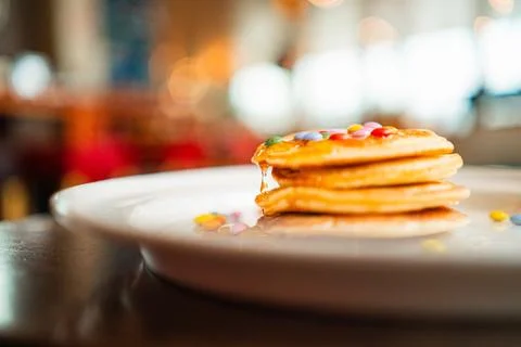Viscouse Honey Dripping Down a Stack Pile of Pancakes with Colorful Topping Stock Photos
