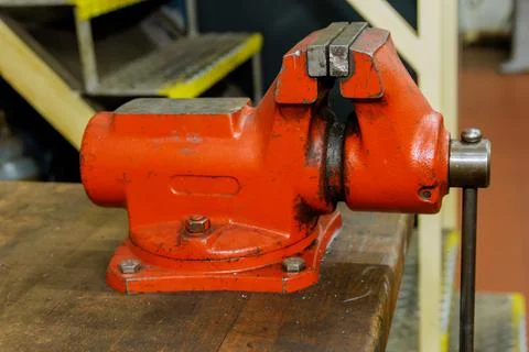 The vise is fixed on the metalworking workbench. Red vise on a wooden table Foto stock