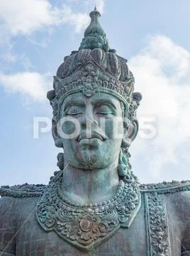 Vishnu monument close up at sunny day with blue sky and moving clouds in Bali Stock Photos