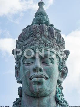 Vishnu monument close up at sunny day with blue sky and moving clouds in Bali Stock Photos