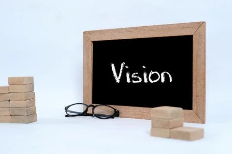 Vision on the blackboard with chalk writing. Eye glasses and Wood block stack Stock Photos