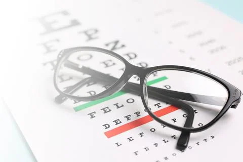 Vision correction glasses on the background of a vision test table with space Stock Photos
