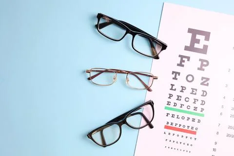 Vision correction glasses on the background of a vision test table with space Stock Photos