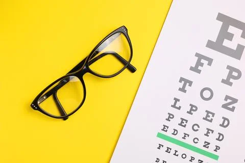 Vision test table and glasses with a colored background. Stock Photos